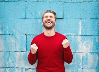 Man in red sweater smiling with fists closed - Outstanding Ways To Seize The Day