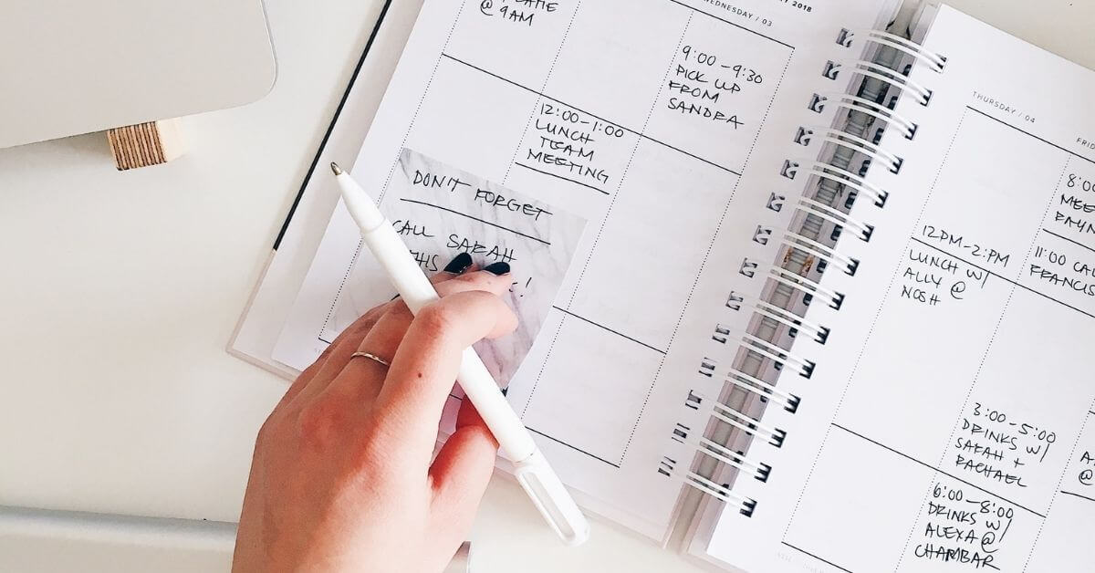 woman's hand over a calendar, planning her week