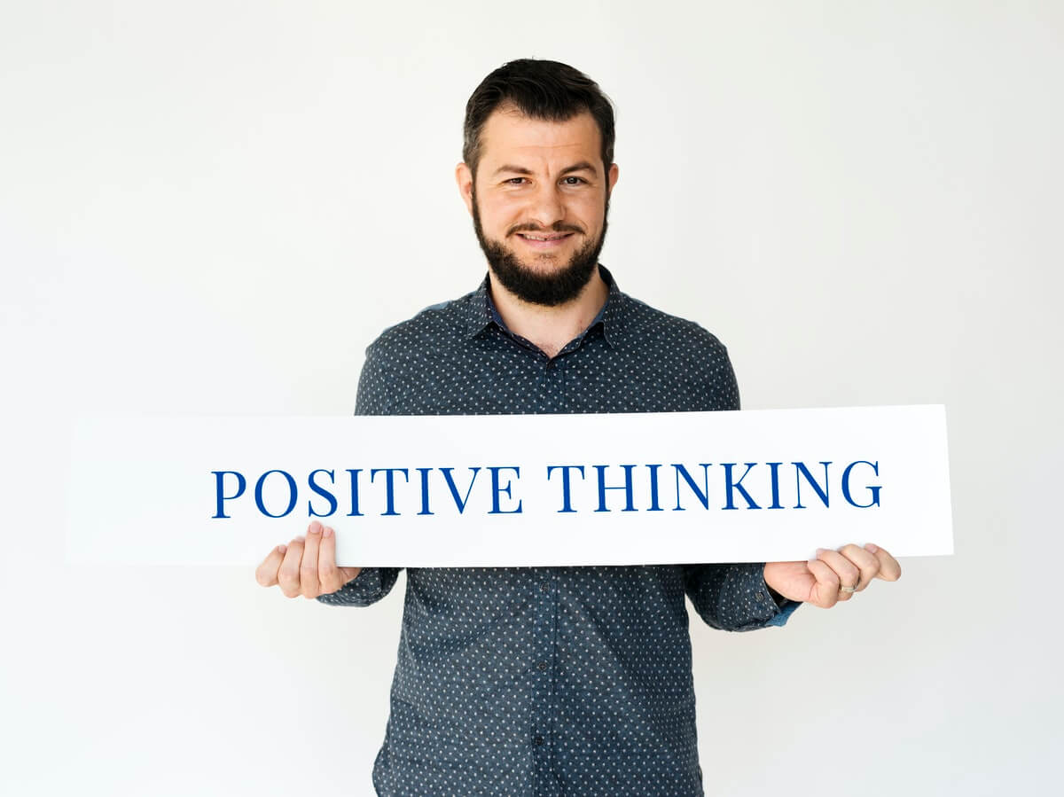 Overcome Your Job Search Blues - A man carrying a banner saying "Positive Thinking" - overcome your job hunting woes