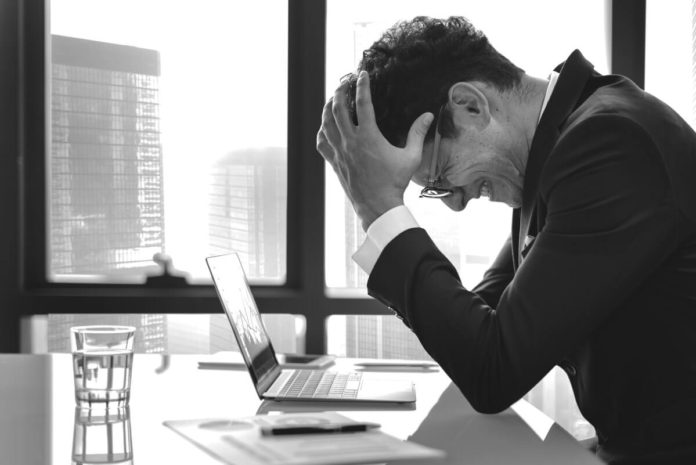 frustrated man at his desk - Reasons Preventing You From Being More Successful